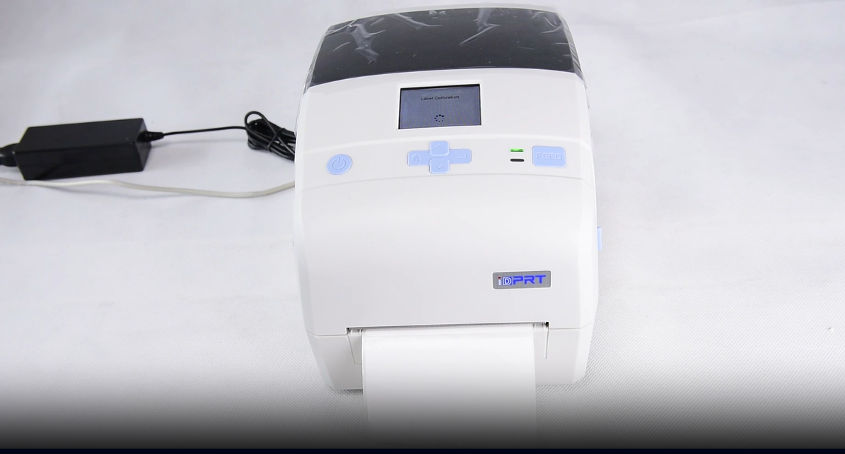 Barcode printer on a desk with a laptop.